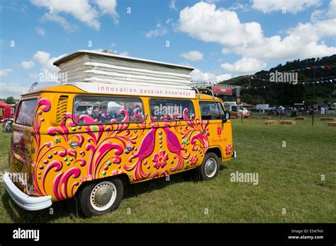 Brightly colored/painted VW camper van in field during show Bakewell ...