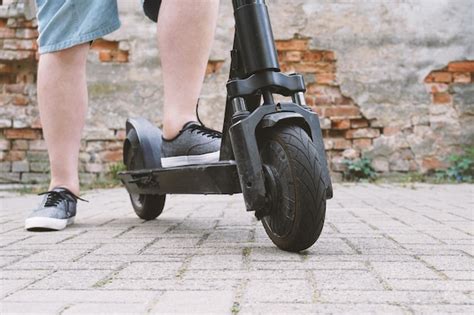 Piernas de hombre irreconocible con patinete eléctrico o scooter Foto