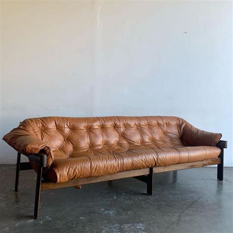 A Brown Leather Couch Sitting On Top Of A Metal Frame Floor Next To A