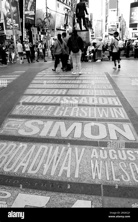 People Walking Past The Names Of Theatres And Artists In Times Square