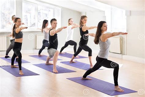 Group Of Sporty People Practicing Yoga With Instructor Warrior Stock