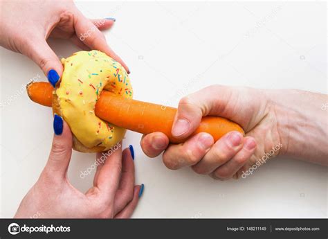 Hands With Carrot Inside Donut Hole Symbol Of Sex Stock Photo