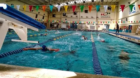 People Swimming In An Indoor Pool With Flags Hanging From The Ceiling