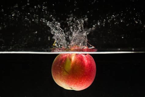 Red Apple Falling In Water With Splash On Black Background Stock Photo