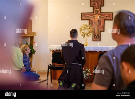 A Franciscan Friar With The Faithful Adoring Jesus In The Most Blessed Sacrament During Prayer