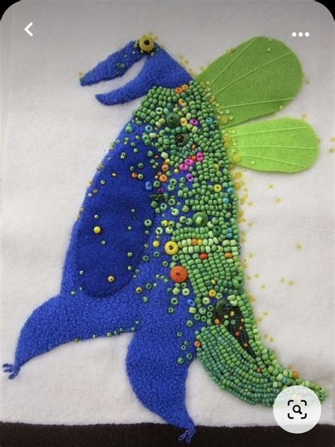 A Piece Of Art Made Out Of Beads And Fabric With A Green Leaf On It