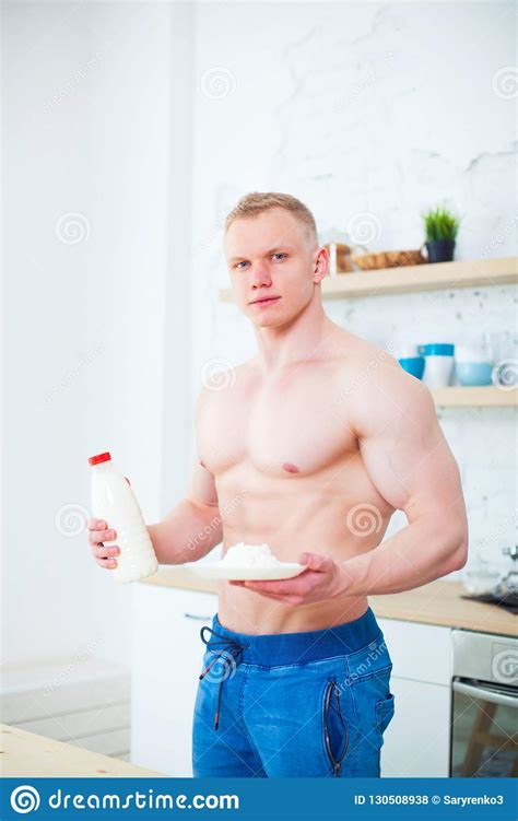 Muscular Man With A Naked Torso In The Kitchen With Milk And Cottage