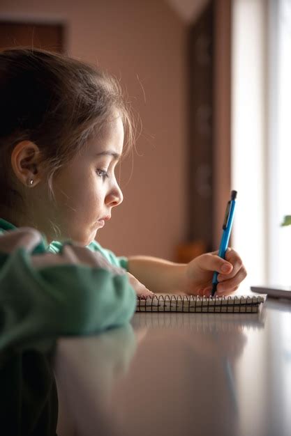 Ni A Seria Escribe Con Un Bol Grafo En Un Cuaderno Foto Gratis