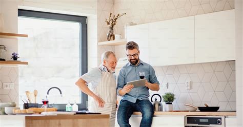 A Portrait Of Adult Hipster Son And Senior Father Indoors In Kitchen At