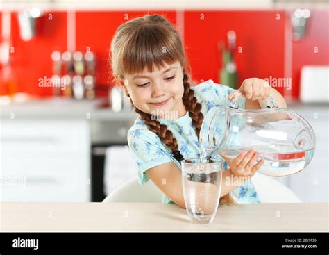 Adorable Little Girl Pouring Water In Kitchen Stock Photo Alamy