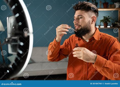 Male Beauty Blogger Recording Live Video Applying Beard Serum While Talking About Skin Care On