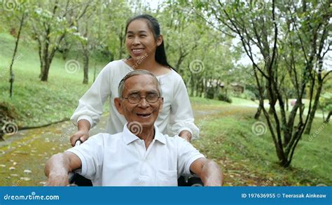 Happy Smiling Grandfather In Wheelchair Relaxing And Walking With