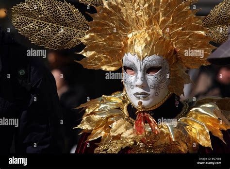 Close Up Of A Venetian Man Woman Wearing A White Mask And Red And Gold Costume In Venice