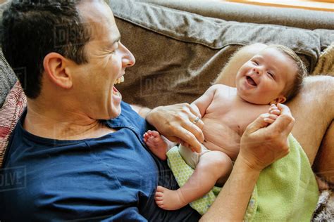 Caucasian Father Laughing With Baby Boy On Sofa Stock Photo Dissolve