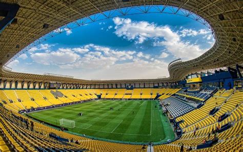 an empty soccer stadium with yellow seats and blue sky in the backgrouds