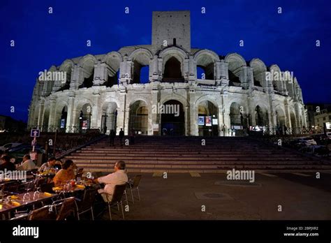 The night view Arles Amphitheatre and medieval tower with outdoor cafe ...