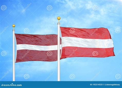 Latvia and Austria Two Flags on Flagpoles and Blue Sky Stock ...