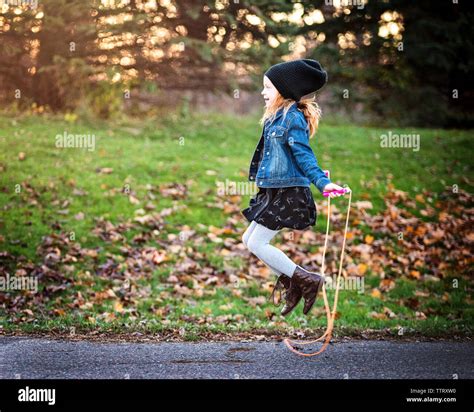 Side View Of Girl Jumping Rope On Footpath At Park During Autumn Stock