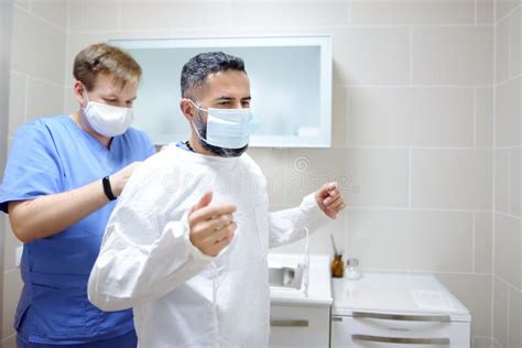 The Assistant Helps The Surgeon To Put On A Medical Surgical Uniform