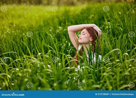 Cute Woman With Red Hair Sits In Tall Green Grass With Her Hand On Her Head Stock Image Image