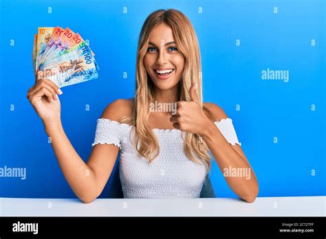 Schöne blonde junge Frau hält schweizer Franken Banknoten lächeln