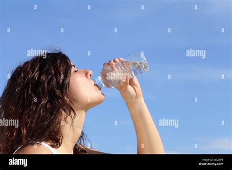 Perfil de una mujer bebiendo agua de una botella de plástico con un