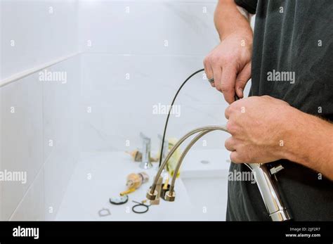 As A Plumber At Work He Is Assembling And Installing The Water Faucet