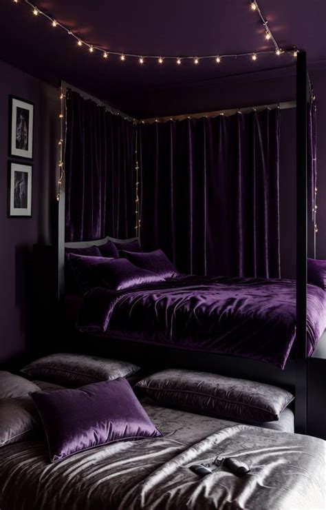 A Bed With Purple Sheets And Pillows In A Room That Has String Lights