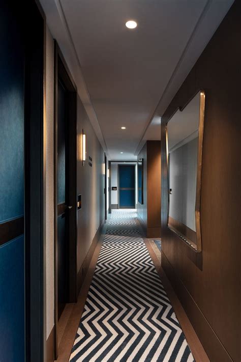 An Empty Hallway With Blue Walls And White Chevron Rugs On The Floor