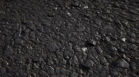 Premium AI Image A Black Asphalt Road With A Few Small Stones And A