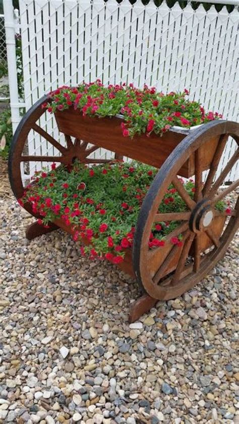 An Old Wooden Wagon With Flowers Growing Out Of It S Wheels On The Gravel