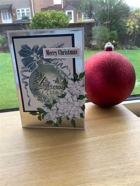 A Christmas Card Sitting Next To A Red Ornament