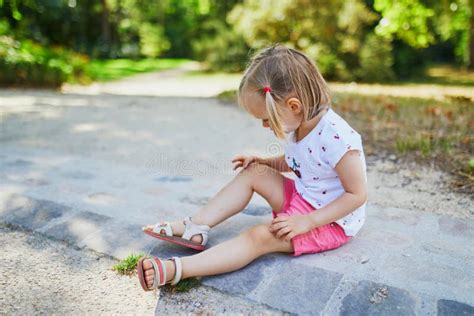 Linda Niña Pequeña Sentada En El Suelo Después De Caer En El Parque De