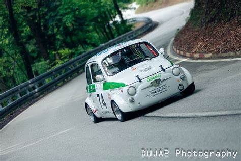 A Small White Car Driving Down A Curvy Road