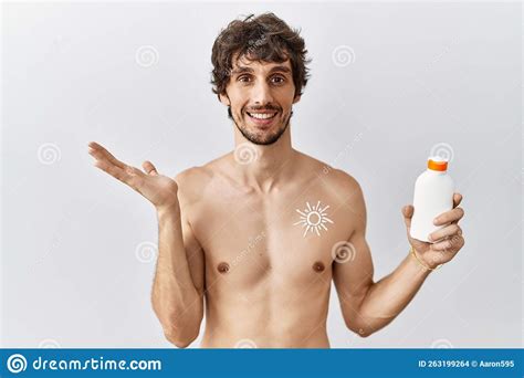 Young Hispanic Man Standing Shirtless Holding Sunscreen Lotion Smiling