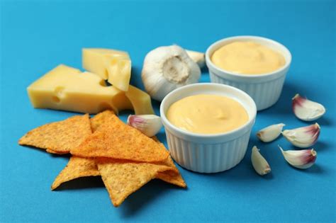 Premium Photo | Cheese sauce, ingredients and chips on blue background