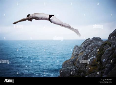 Man diving off cliff Stock Photo - Alamy