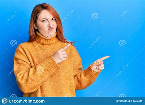 Beautiful Redhead Woman Pointing Fingers To The Side Skeptic And Nervous Frowning Upset Because