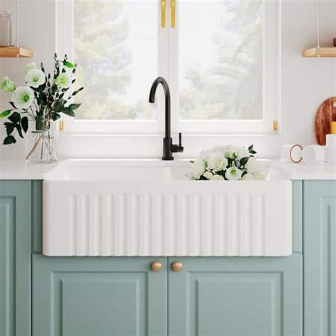 A White Kitchen Sink Sitting Under A Window Next To A Counter Top With