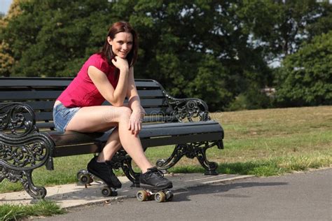 A Menina Bonita Amarra Patins De Rolo No Banco De Parque Foto De Stock