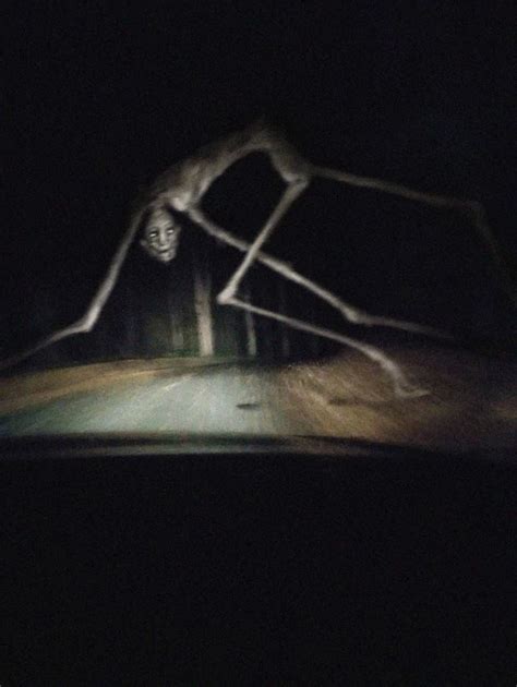 A Creepy Figure Is In The Middle Of A Dark Road At Night With Headlights On