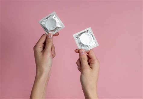 2 Hands Holding Up Condoms To Ask Can You Have Sex On Your Period And