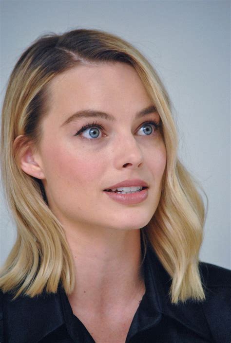 a woman with blonde hair and blue eyes looks at the camera while wearing a black shirt