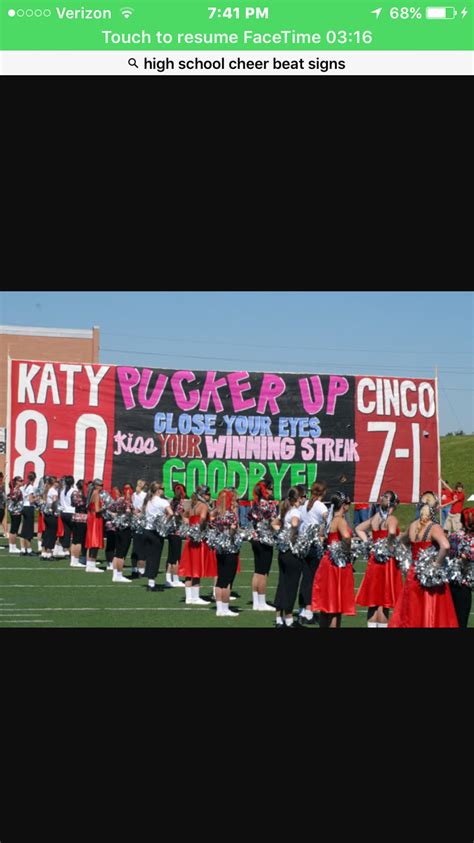 a group of cheerleaders standing in front of a large sign that reads ...