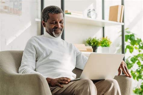 Sorrindo Homem Afro Americano Sentado Na Poltrona E Usando O Laptop