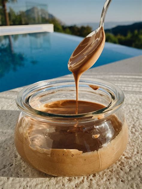 A Spoon Pouring Peanut Butter Into A Glass Jar With A Swimming Pool In