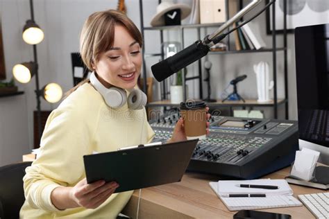 Woman With Cup Of Coffee Working As Radio Host In Modern Studio Stock