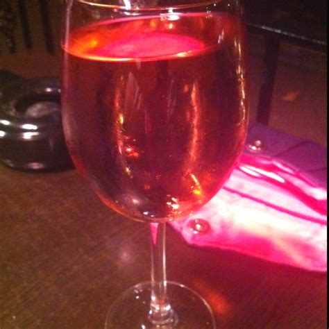 A Glass Of Wine Sitting On Top Of A Wooden Table Next To A Pink Cloth