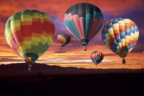 Three Hot Air Balloons Are Flying In The Sky At Sunset With Mountains