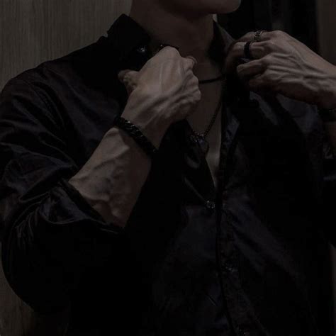 A Man In Black Shirt Tying His Tie